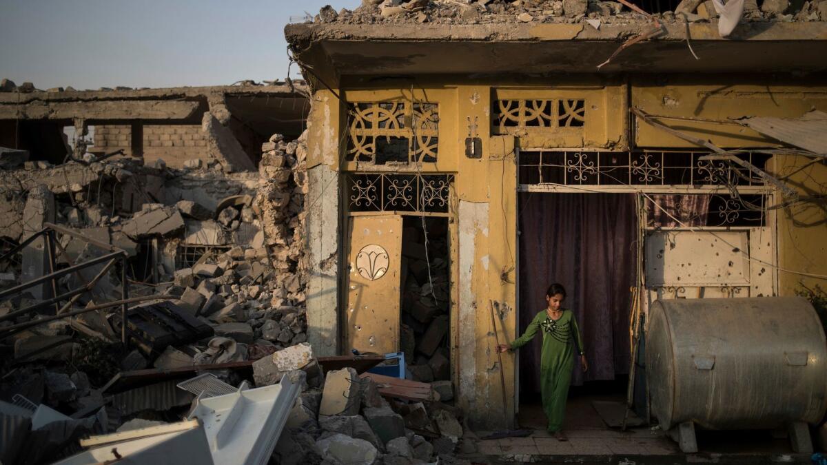 Samaher Saddam cleans the entrance of her damaged house in the west side of Mosul, Iraq.