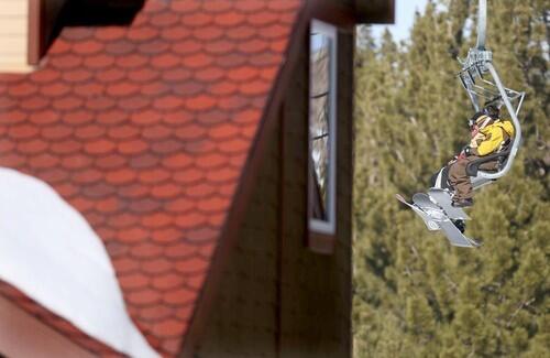 Skiers ride a ski lift by the Eagle Run condos in Mammoth Mountain.