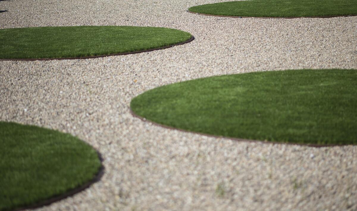 A Long Beach couple changed their front landscape into a drought tolerant work of art, including bold circles of rock and artificial grass in front of a 1930s vintage home.
