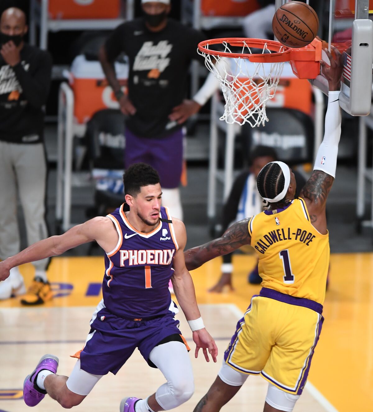Lakers guard Kentavious Caldwell-Pope scores a basket in front of Suns guard Devin Booker.