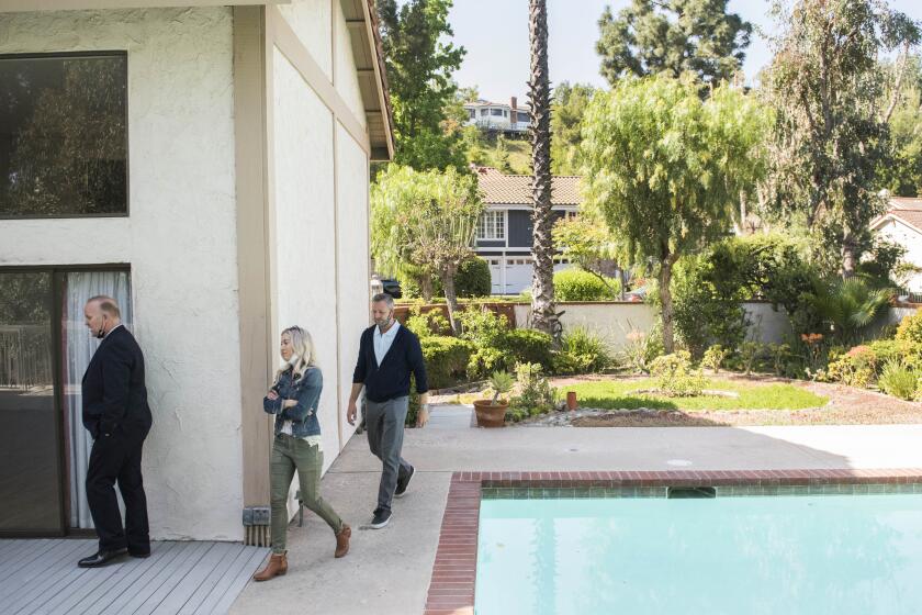 Real estate agent Derek Oie, left, shows a home to his clients Sarah and Vik Szemerei in North Tustin during their allotted 30 minute time slot on Saturday, April 17, 2021. ( Photo by Nick Agro / For The Times )