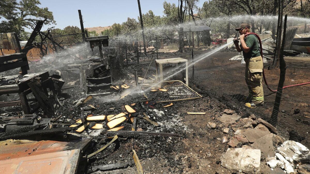 A firefighter douses embers at the site of a blaze in Moab, Utah, which destroyed eight homes.