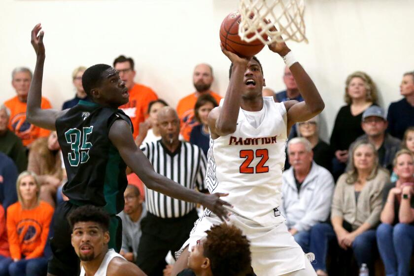 Pacifica Christian’s Judah Brown (22) stops for a short pull up jumper(34) next to Fairmont Prep’s Pape Cisse during San Joaquin League game on Friday.