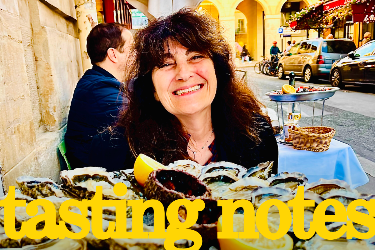 Ruth Reichl smiling with a platter of oysters while seated along a street in Paris. In foreground, the words "tasting notes."