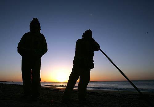 As the sun rises, firefighters stand watch along Malibu Road.