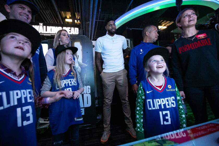 Los Angeles, CA., December 18, 2019: Reese Robertson, 5, and her family plays a game as LA Clippers star Paul George looks on at his third annual Christmas Celebration at Dave and Busters on Wednesday, December 18, 2019 in Los Angeles, California. The Paul George Foundation has partnered with the American Stroke Association to bring families impacted by stroke together for a fun filled evening. (Jason Armond / Los Angeles Times)