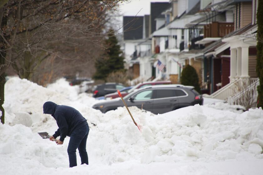 FILE - A person removes snow from the front of his driveway a few days after a winter storm rolled through western New York Thursday, Dec. 29, 2022, in Buffalo, N.Y. A new report finds several shortcomings in Buffalo's response to a historic December blizzard in which 31 city residents died. The report was released Friday, June 2, 2023, by the New York University Wagner School for Public Service. (AP Photo/Jeffrey T. Barnes, File)