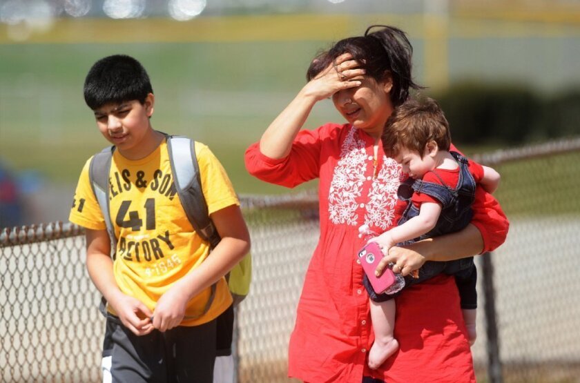 Erum Naqvi holds her son Ayan as she picks up her son Raza Naqvi, left, after a stabbing rampage at Franklin Regional Senior High School in Murrysville, Pa.