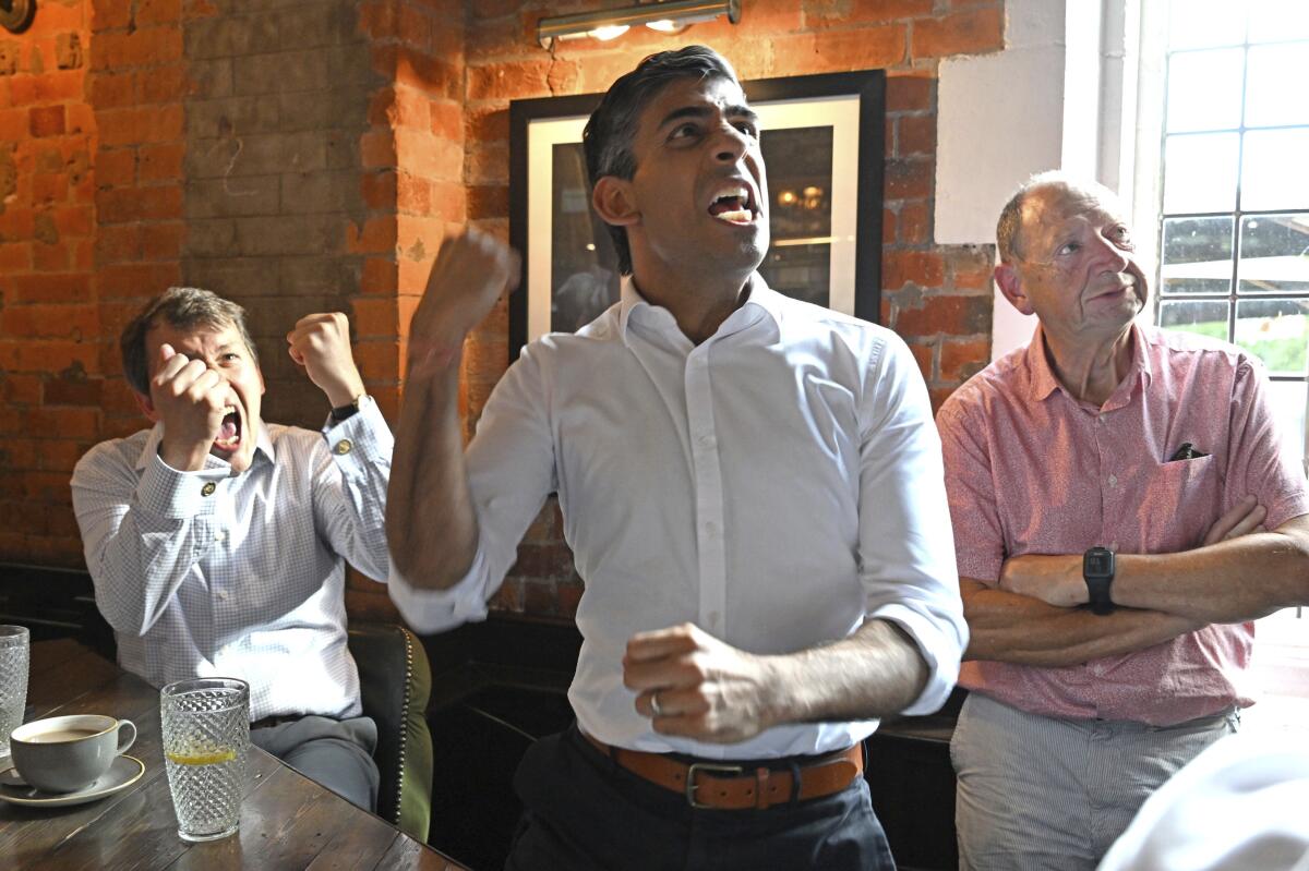 Rishi Sunak in Salisbury with MP John Glen, left, celebrates England's first goal while watching a screening of the UEFA Women's Euro 2022 final held at Wembley Stadium, Sunday July 31, 2022. (Finnbarr Webster/PA via AP)