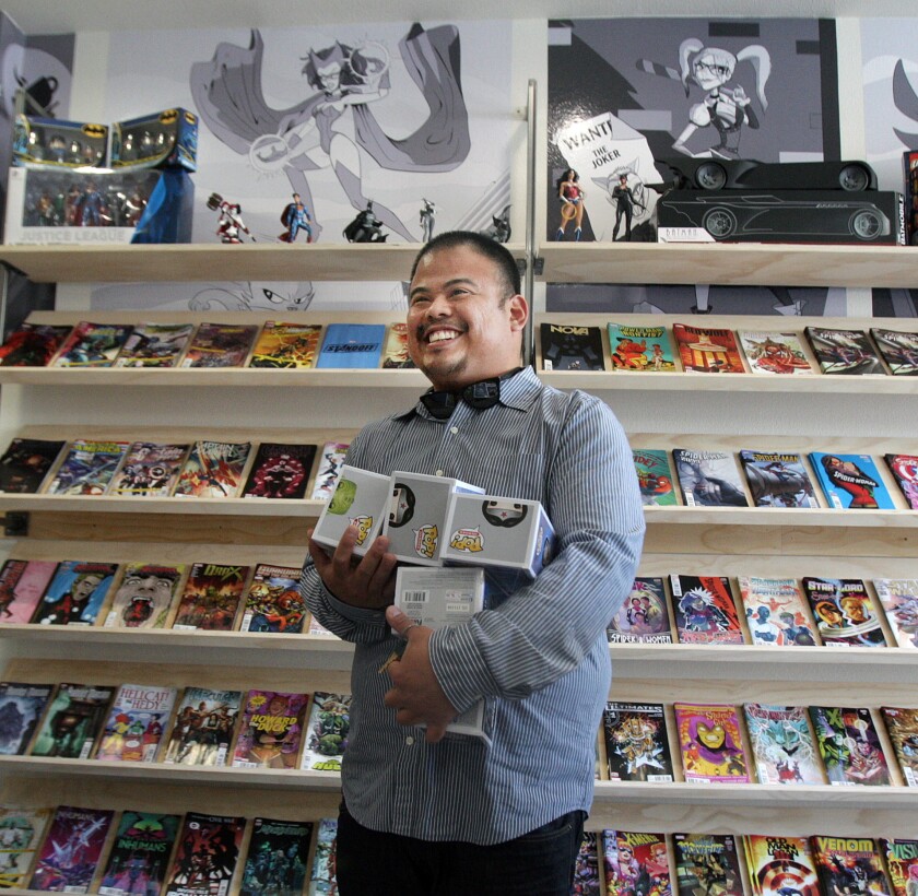 Anthony Dela Cruz, of Arleta carries an armload of Pop Heroes that he intends to purchase at The Perky Nerd, a 5-day old comic book and coffee store in Burbank on Thursday, April 28, 2016.