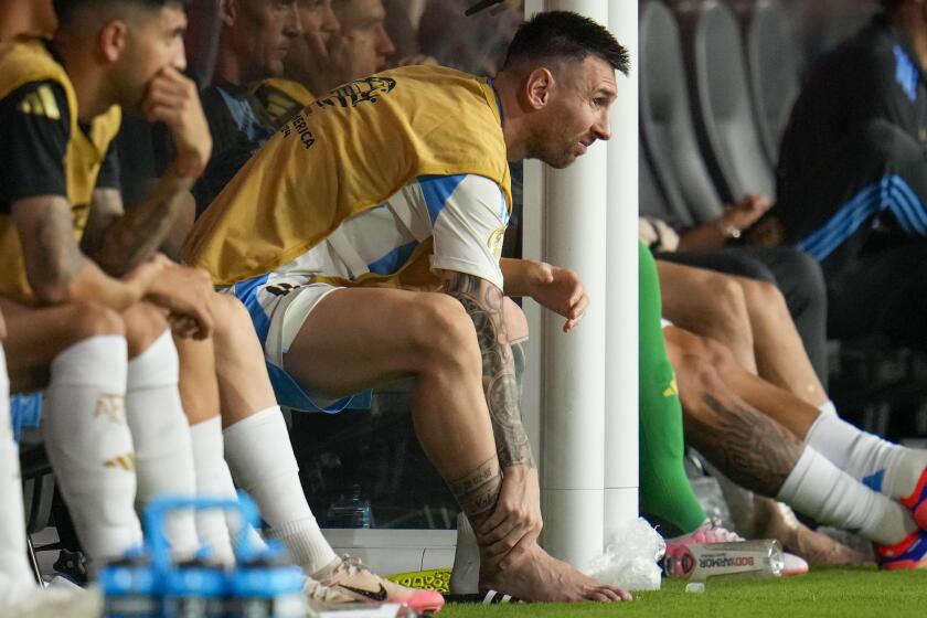 El argentino Lionel Messi se toca el tobillo sentado en el banquillo durante un partido de la final de la Copa América contra Colombia en Miami Gardens, Florida, el domingo 14 de julio de 2024. (AP Foto/Julio Cortez)