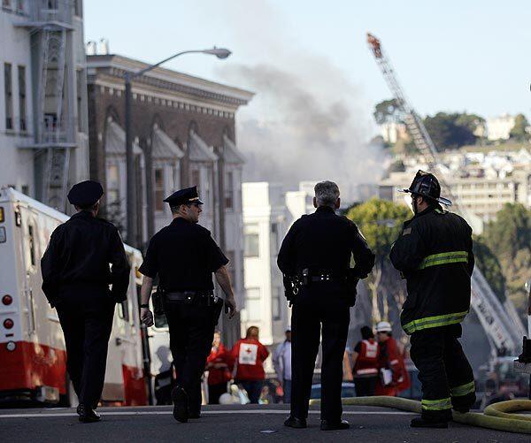 Firefighters and police officers keep watch over an apartment fire in San Francisco's Western Addition on Thursday.