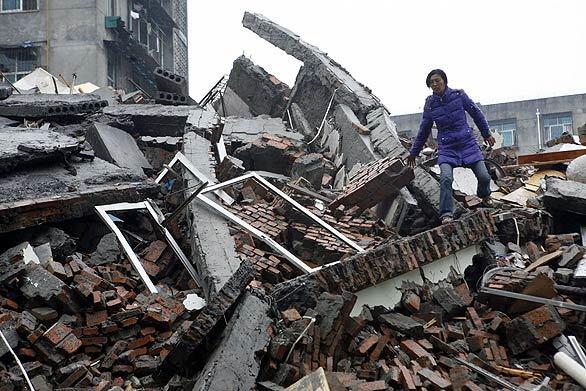 A woman tries to salvage some belongings from a collapsed building in Dujiangyan.