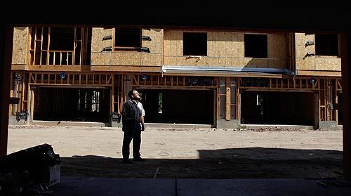 Imperial Valley real estate agent Frederic Din is framed by a vacant garage outside a partly completed home at the Springhouse development in Brawley. The builder went bankrupt and left uncompleted homes and empty lots. Audio slideshow >>>