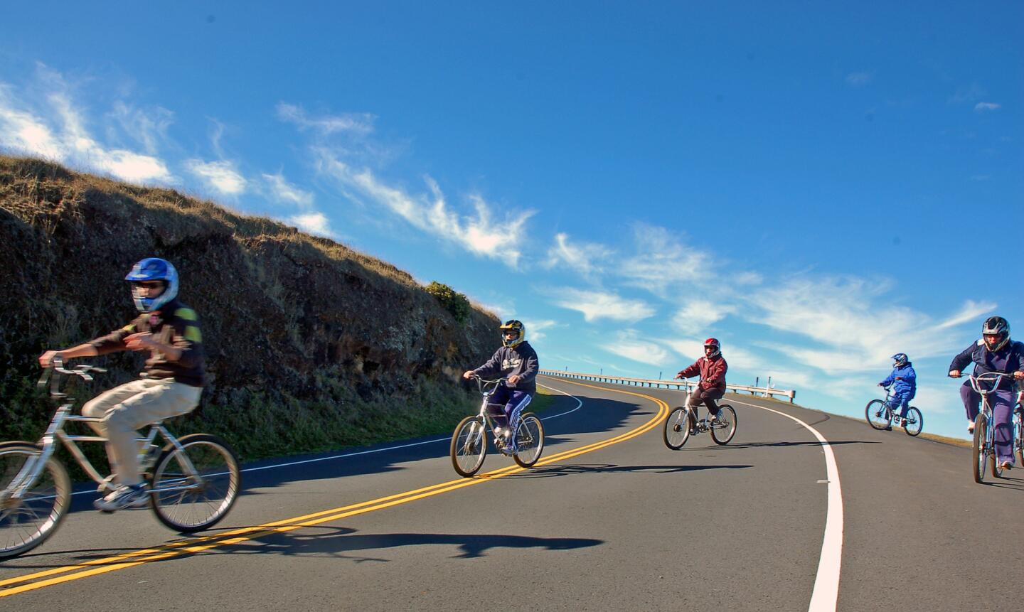 Riders cross back over the road after a scenic viewing stop on their sunrise bike trek down Haleakala, a nearly 10,000-foot volcano on Maui. Every year, thousands of bicyclists take the 27-mile ride to the sea.