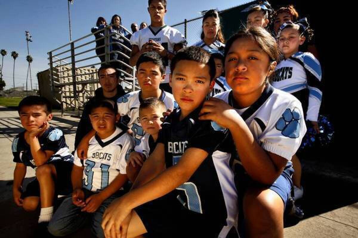 Bobcat team members past and present, along with Bobcat cheerleaders, parents and supporters, pose for a portrait at Salazar Park in East Los Angeles. "The whole team, we're like family," said 8-year-old Jacob Ramos, second from right in front.