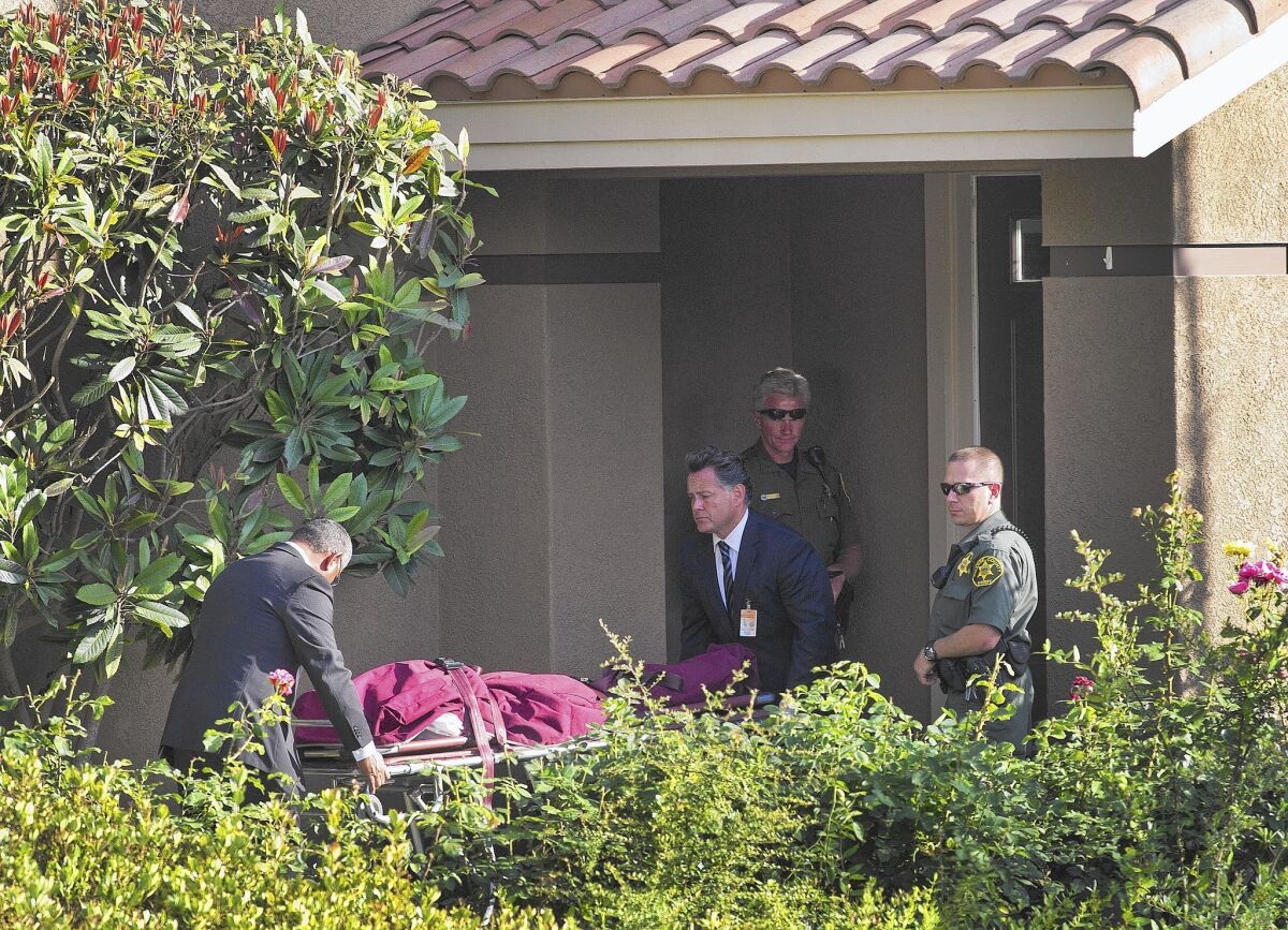 Orange County Sheriff-Coroner's office workers remove a body from a Mission Viejo home, where a family of four was found dead in an apparent murder-suicide.