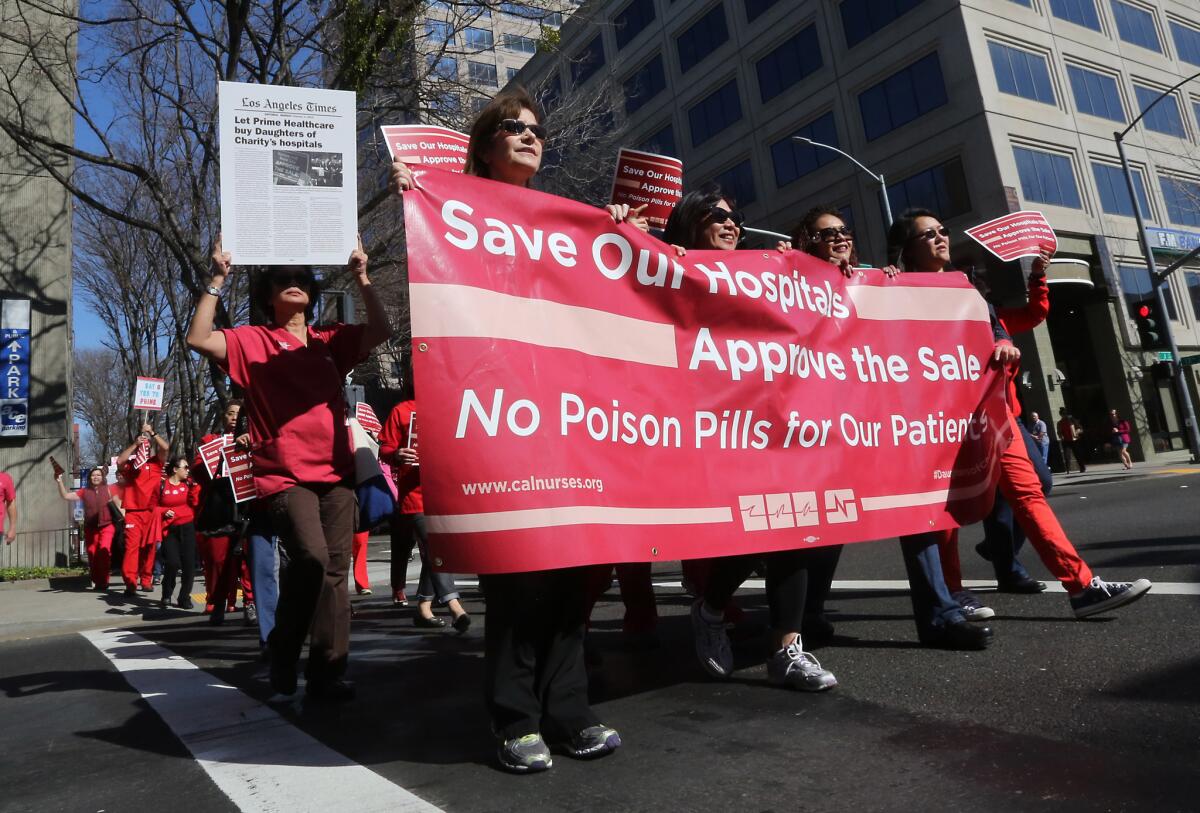 Healthcare workers and supporters are seen last month marching in Sacramento to encourage Atty. Gen. Kamala Harris to approve the sale of six nonprofit hospitals to a for-profit corporation.