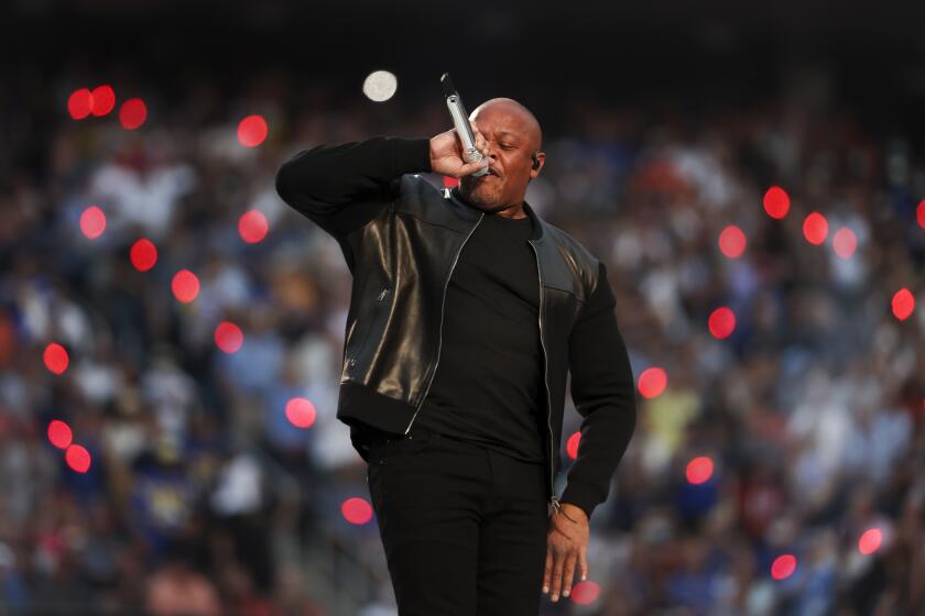 A man vocalizing into a microphone and wearing an all-black outfit on a stage