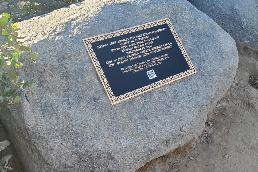 A plaque on a rock on Coast Walk Trail includes a message written in Kumeyaay and a QR code for an augmented reality experience at the site.