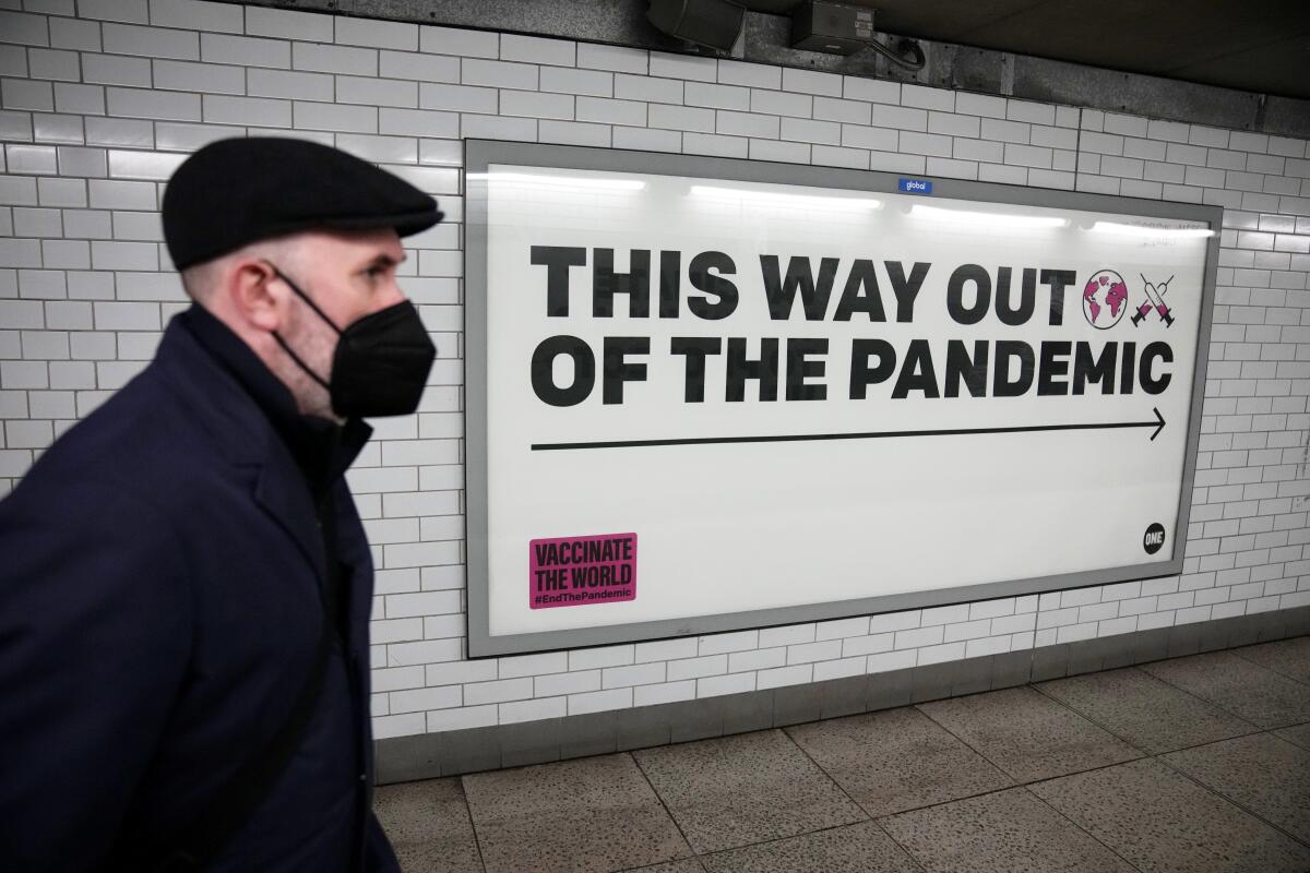 A man wearing a face mask walks past a health campaign poster in London.