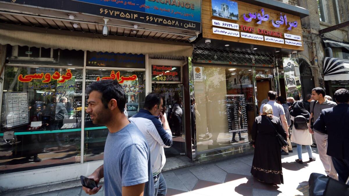 Iranians check the currency rate around a money exchange shop in Tehran.