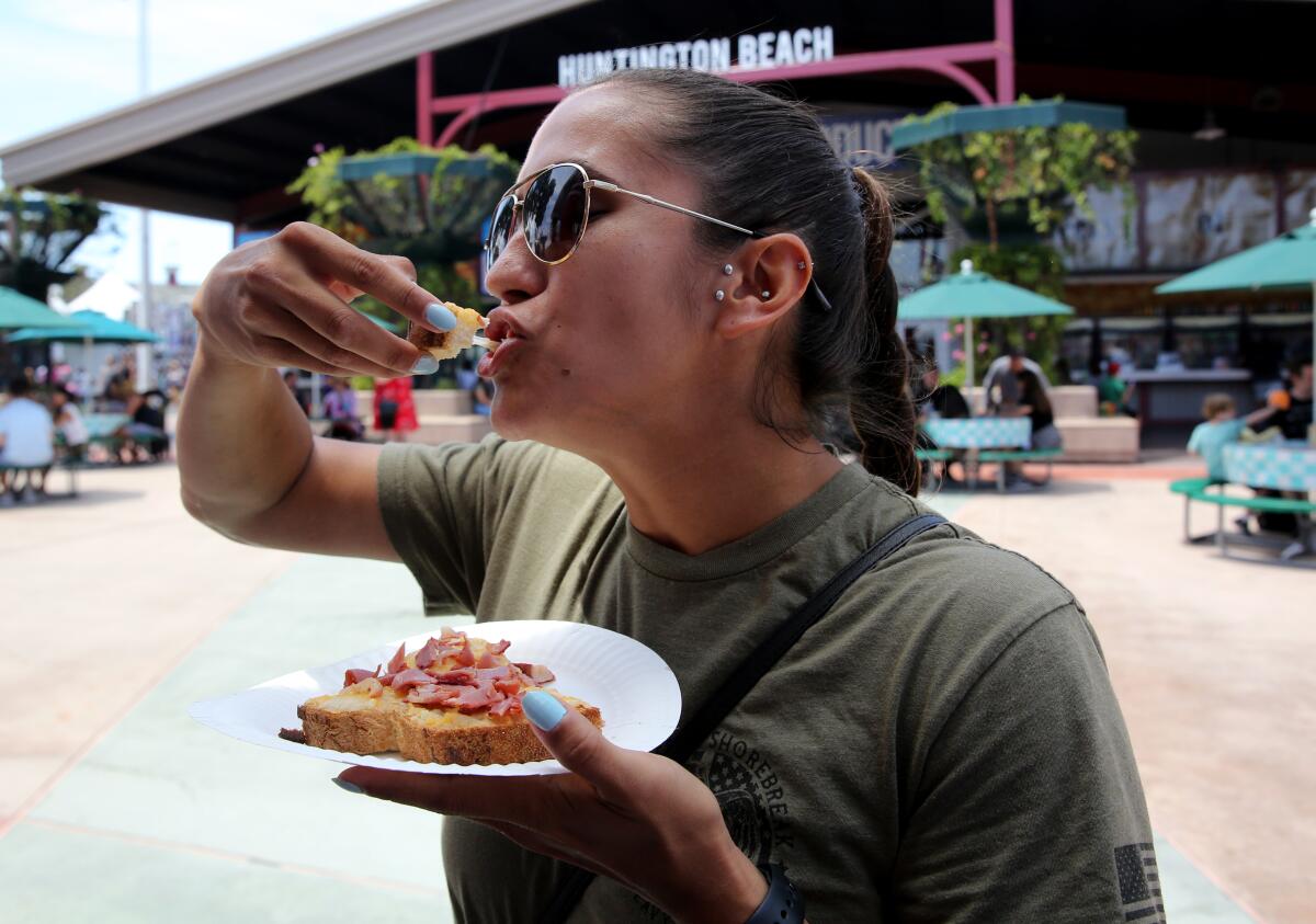 Rochelle Rivera of Huntington Beach takes a bite of her pastrami on sourdough with cheese at the Orange County Fair.