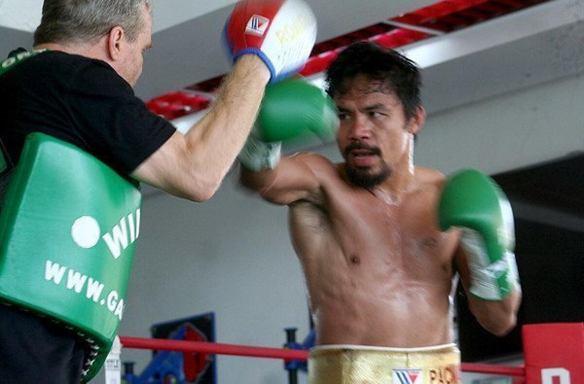 Former champion boxer Manny Pacquiao spars with trainer Freddie Roach at a gym in General Santos City last month.