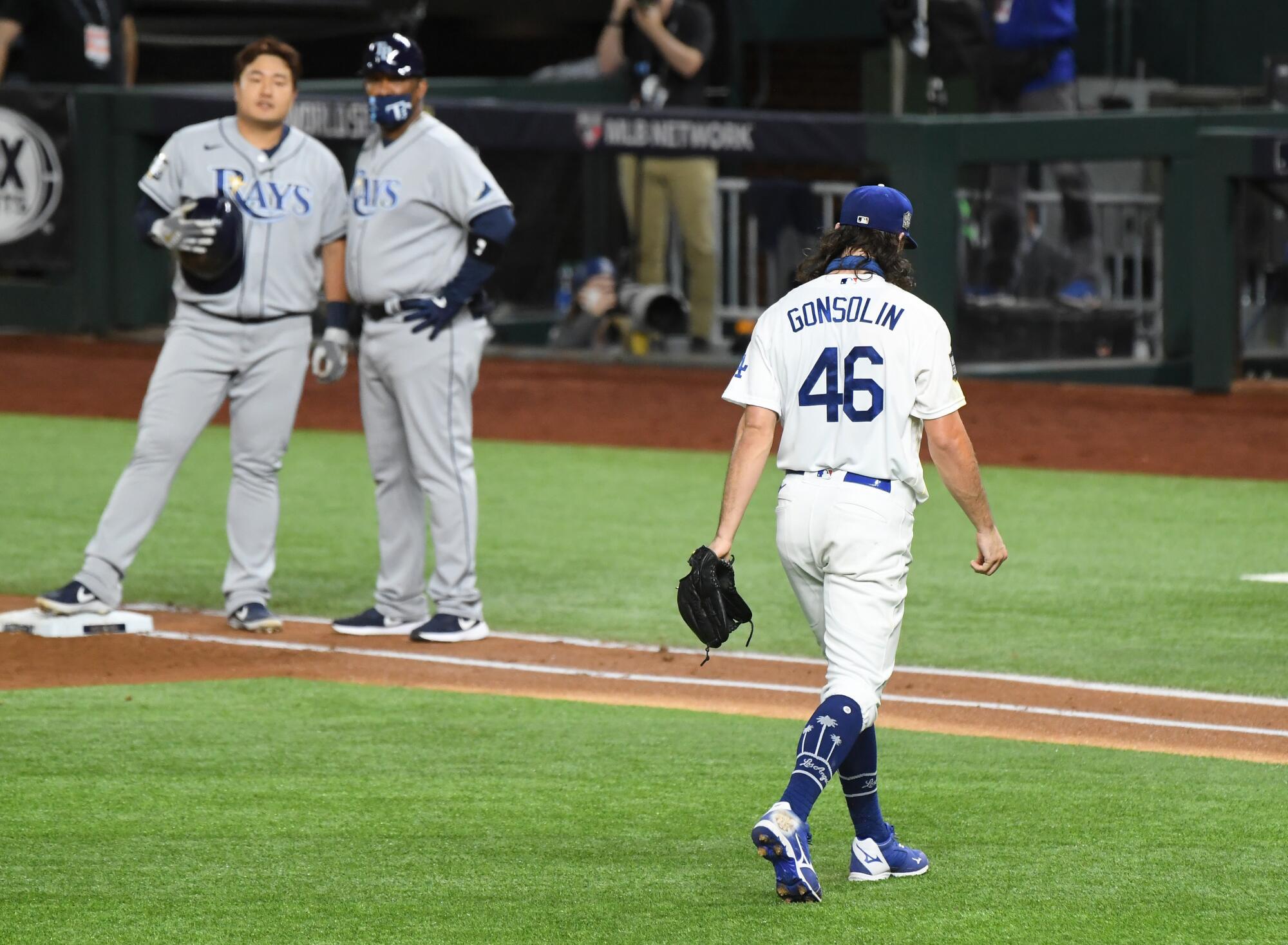 Dodgers starter Tony Gonsolin walks off the field past the Rays' Ji-Man Choi, standing on first base.