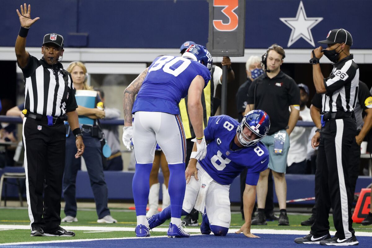 New York Giants tight end Kyle Rudolph (80) checks on quarterback Daniel Jones (8) after Jones was tackled short of the end zone in the first half of an NFL football game against the Dallas Cowboys in Arlington, Texas, Sunday, Oct. 10, 2021. Jones suffered and unknown injury on the play. (AP Photo/Michael Ainsworth)