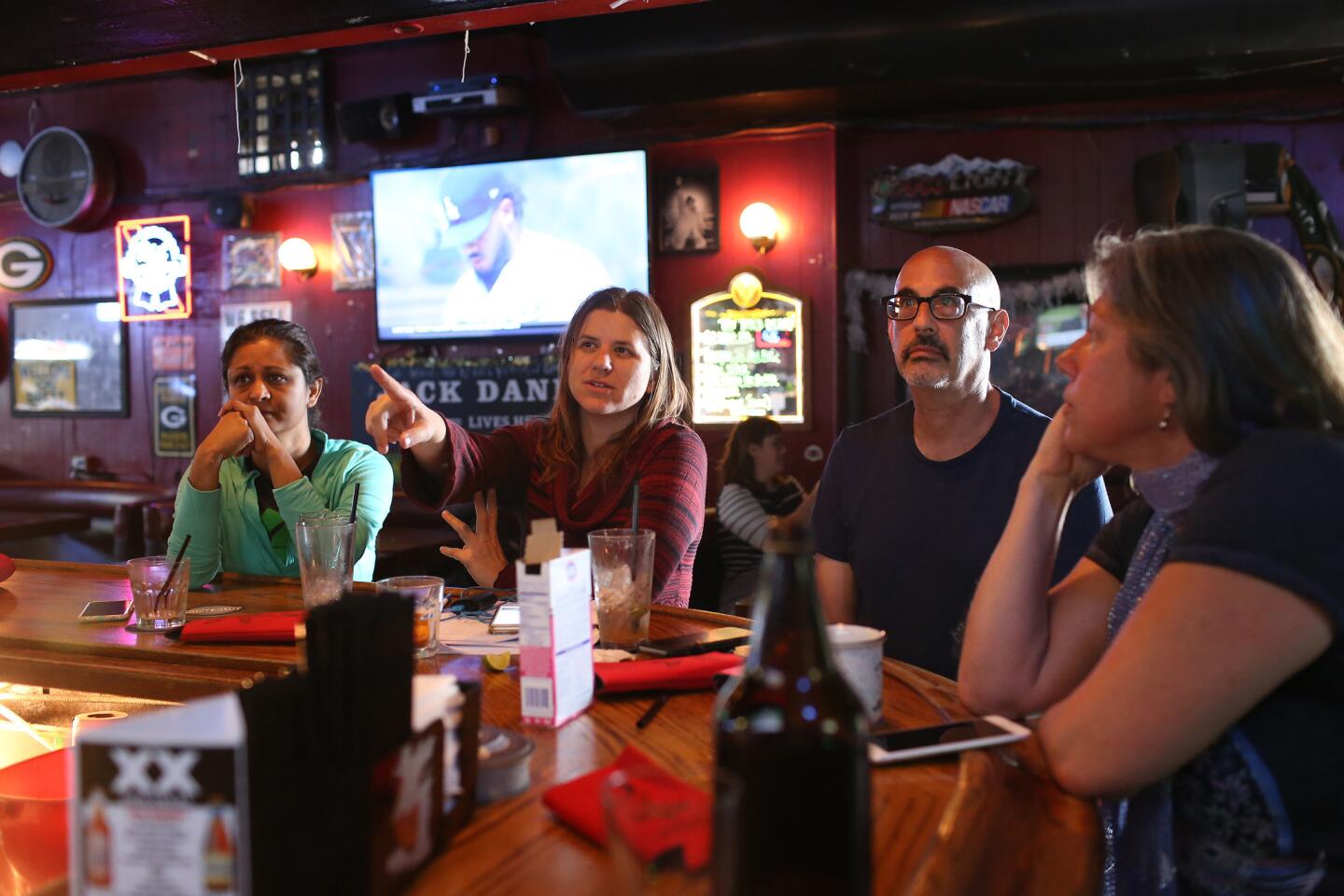 Tahmina Khan, Annette Morasch, Scott Malsin and Maya Grafmuller gather at the bar of the Tattle Tale Room to watch the public testimony of former FBI director James Comey during an investigative hearing being shown live on television.