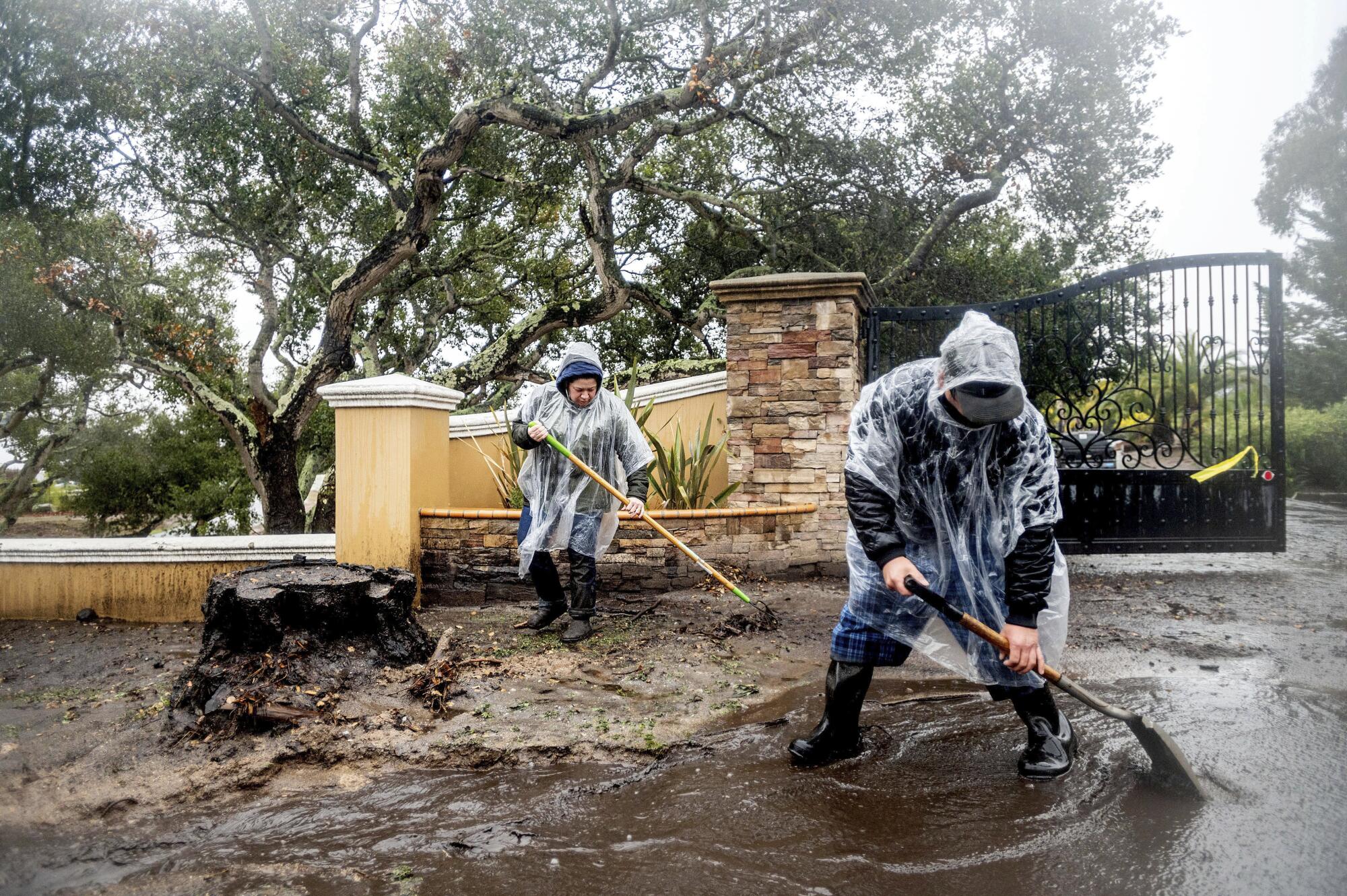 Alex and Aron Moreno work to divert water from their property as heavy rains fall in Salinas. 