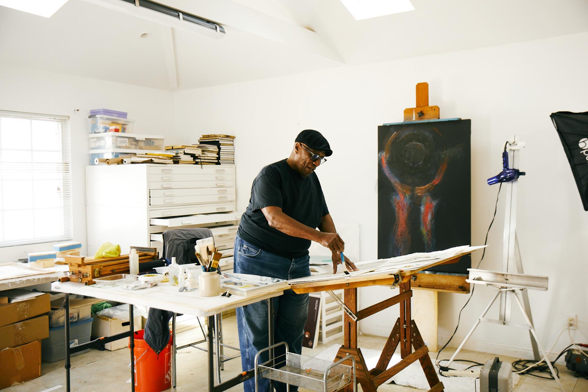 George Evans in his painting studio, an abstract painting on an easel in the background.