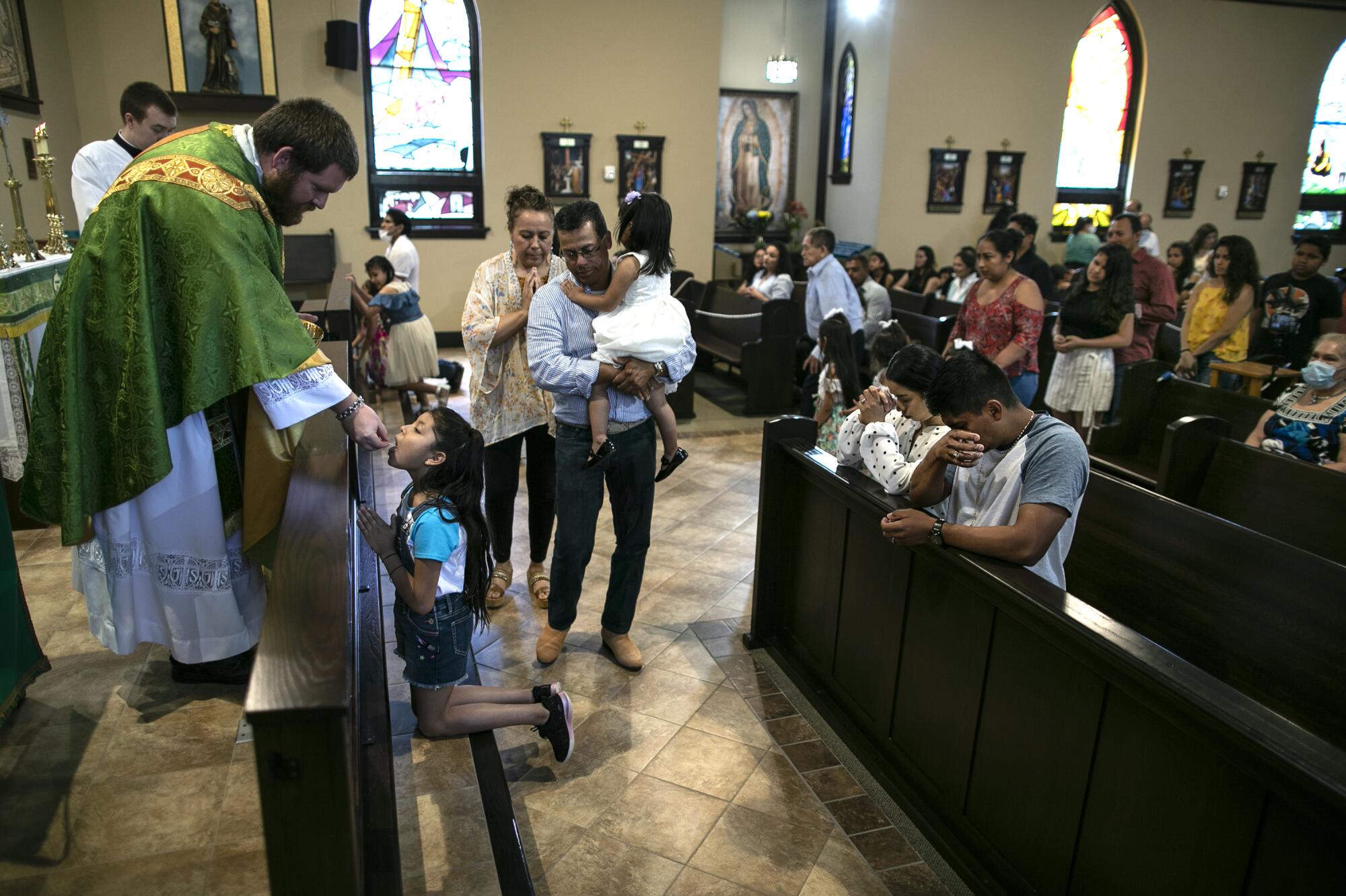 A young girl receives Communion from the Rev. Kristopher Cowles.