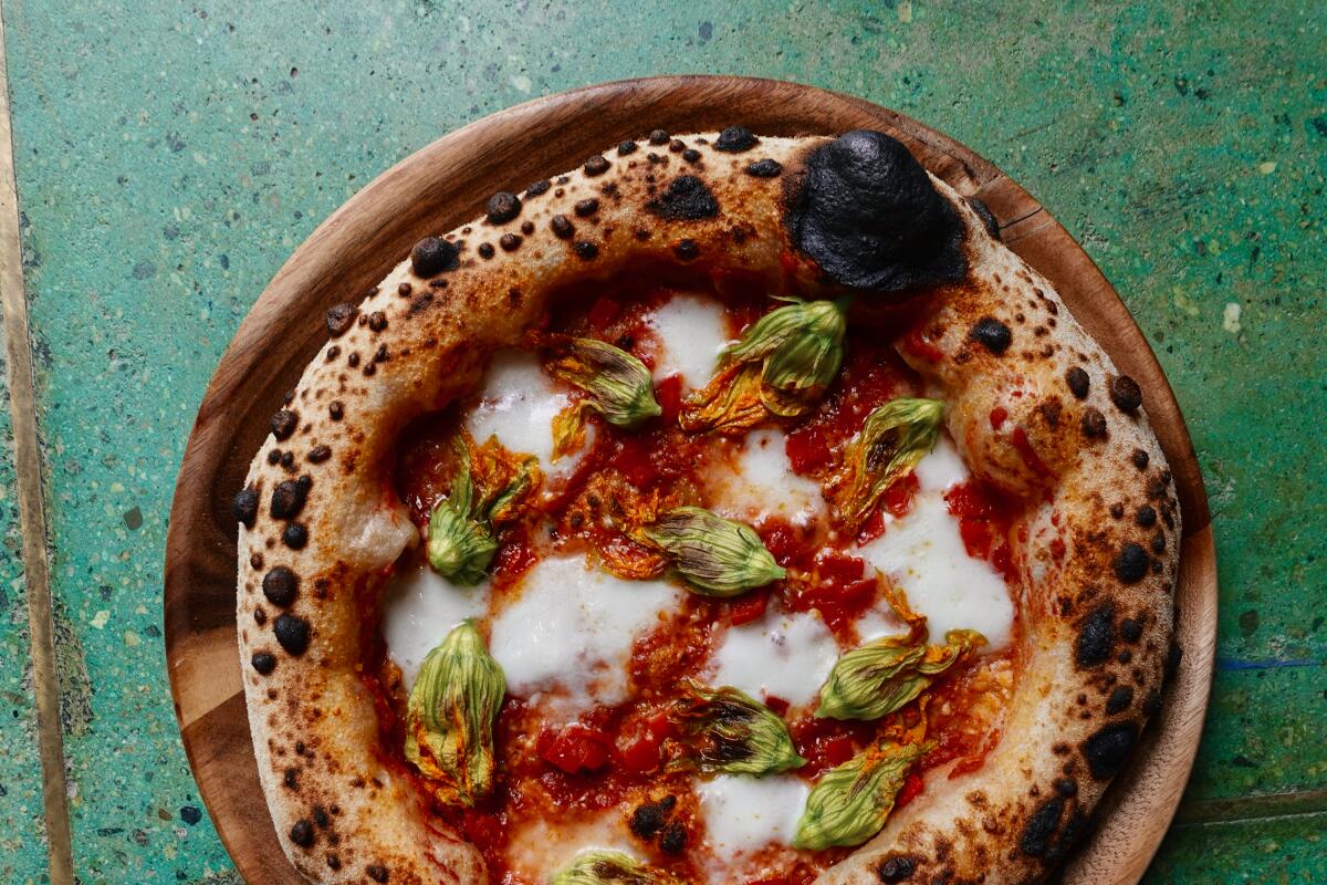 An overhead photo of a Neapolitan-style pizza on a green background