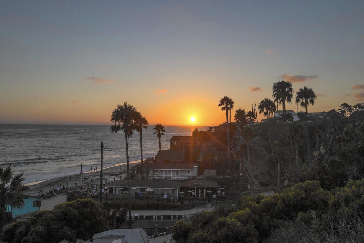 The sun sets over the Crystal Cove cottages in Newport Beach in 2016. On March 8, the state Coastal Commission is to consider a coastal development permit to restore the remaining 17 of the 46 cottages.