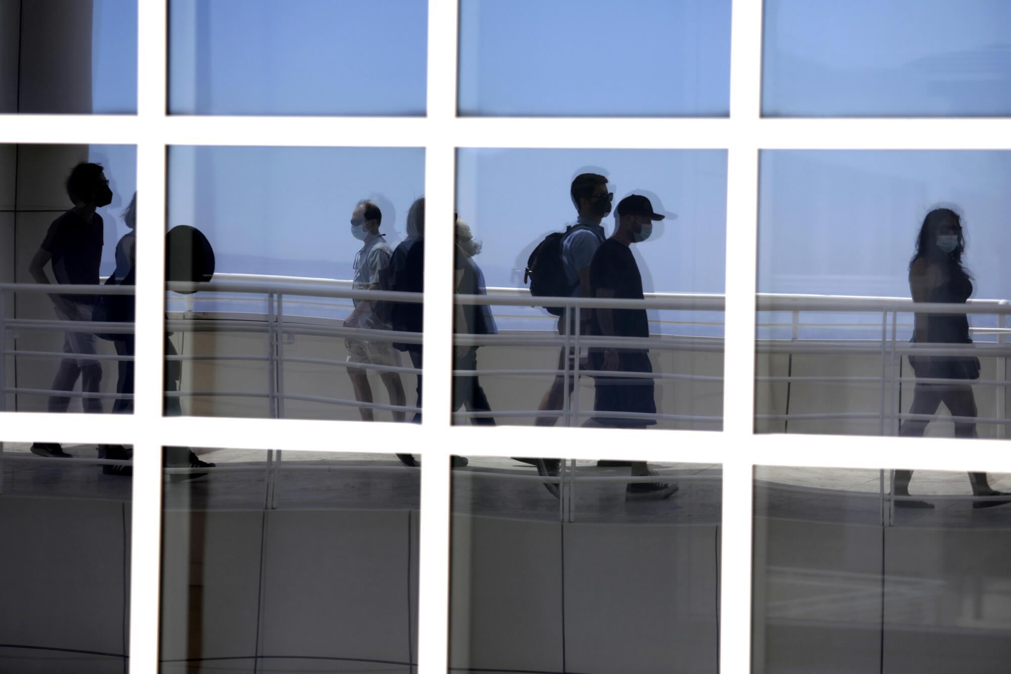 Visitors walking through the Getty Center are reflected in the panes of a window