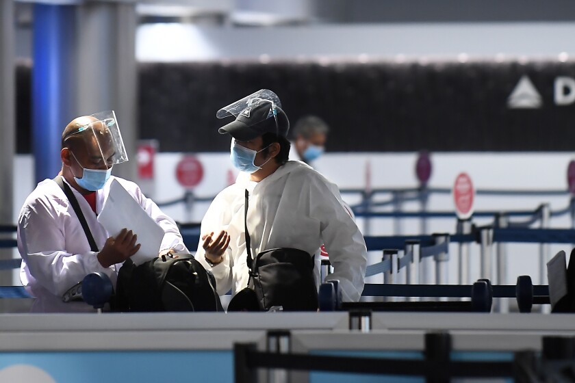 Travelers wearing full body suit sand masks prepare to head to there gate at Terminal 2 at LAX Friday.  