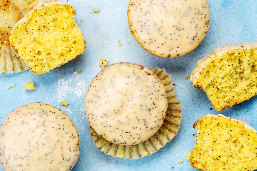 Passion fruit and poppy seed muffins, whole and halved, in paper wrappers.