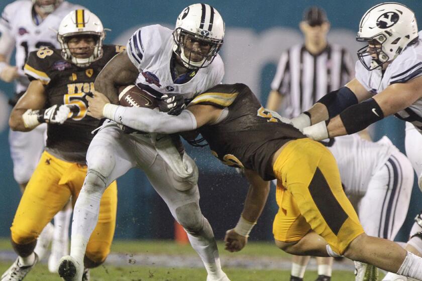 Wyoming's Cassh Maluia tries to stop BYU's Jamaal Williams as he carries the ball in the second quarter of the Poinsettia Bowl on Wednesday.