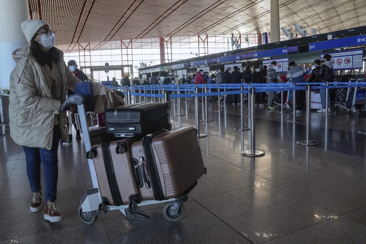 A masked traveler arrives at the international flight check in counter at the Beijing Capital International Airport.