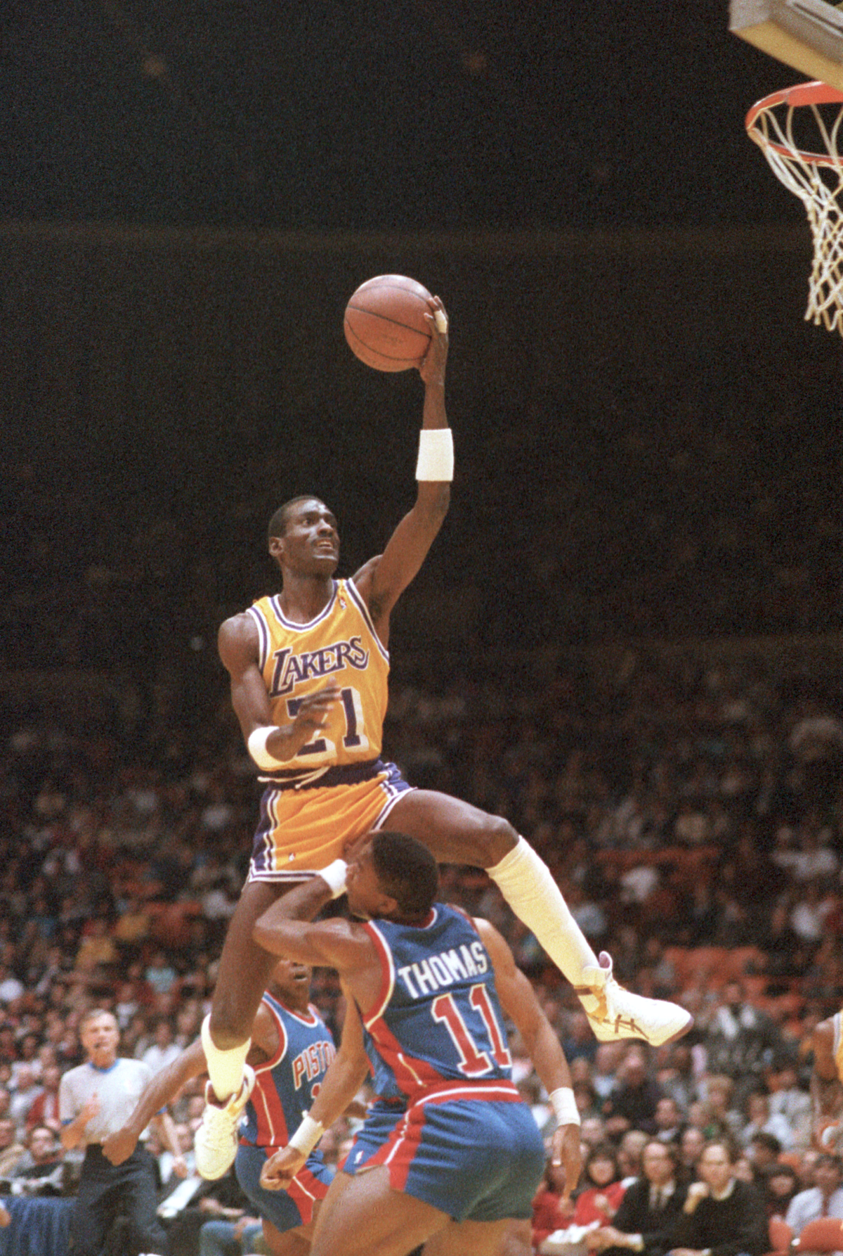 Lakers forveti Michael Cooper, turnike için Pistons guardı Isiah Thomas'ın üzerinden geçiyor.