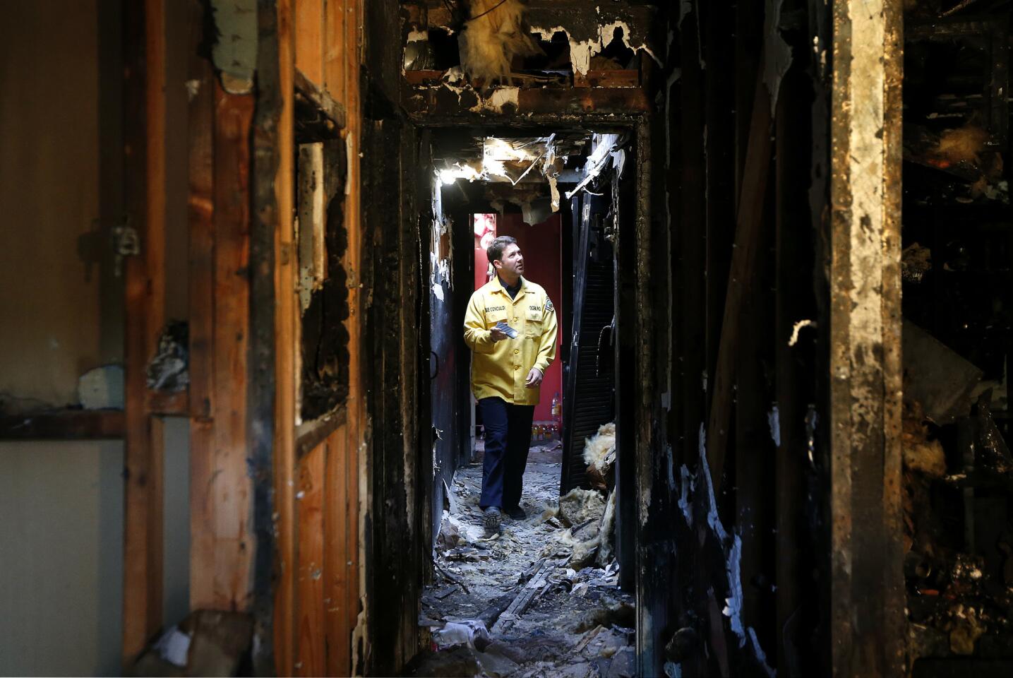Orange County Fire Authority public information officer Steve Concialdi walks through the charred condominium in San Juan Capistrano. A mother and her 3-year-old son have died as a result of the fire.