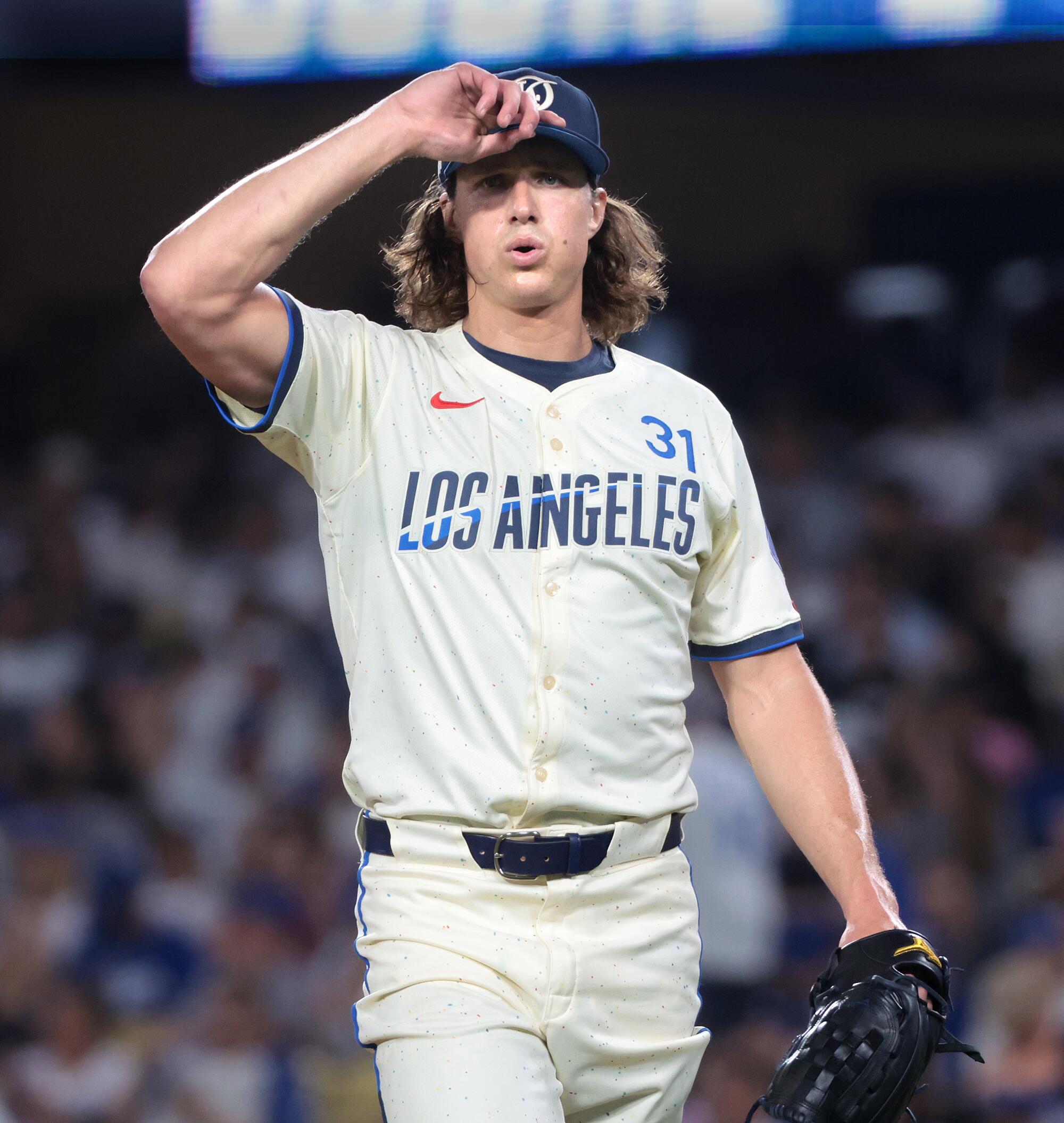 Dodgers pitcher Tyler Glasnow blows out some air and holds the brim of his cap.