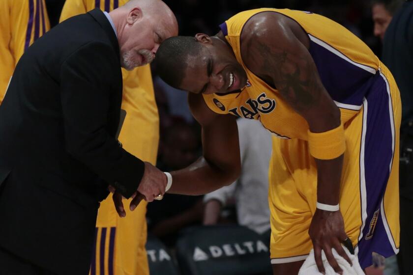Lakers forward Antawn Jamison grimaces in pain Friday as trainer Gary Vitti looks at his injured wrist.