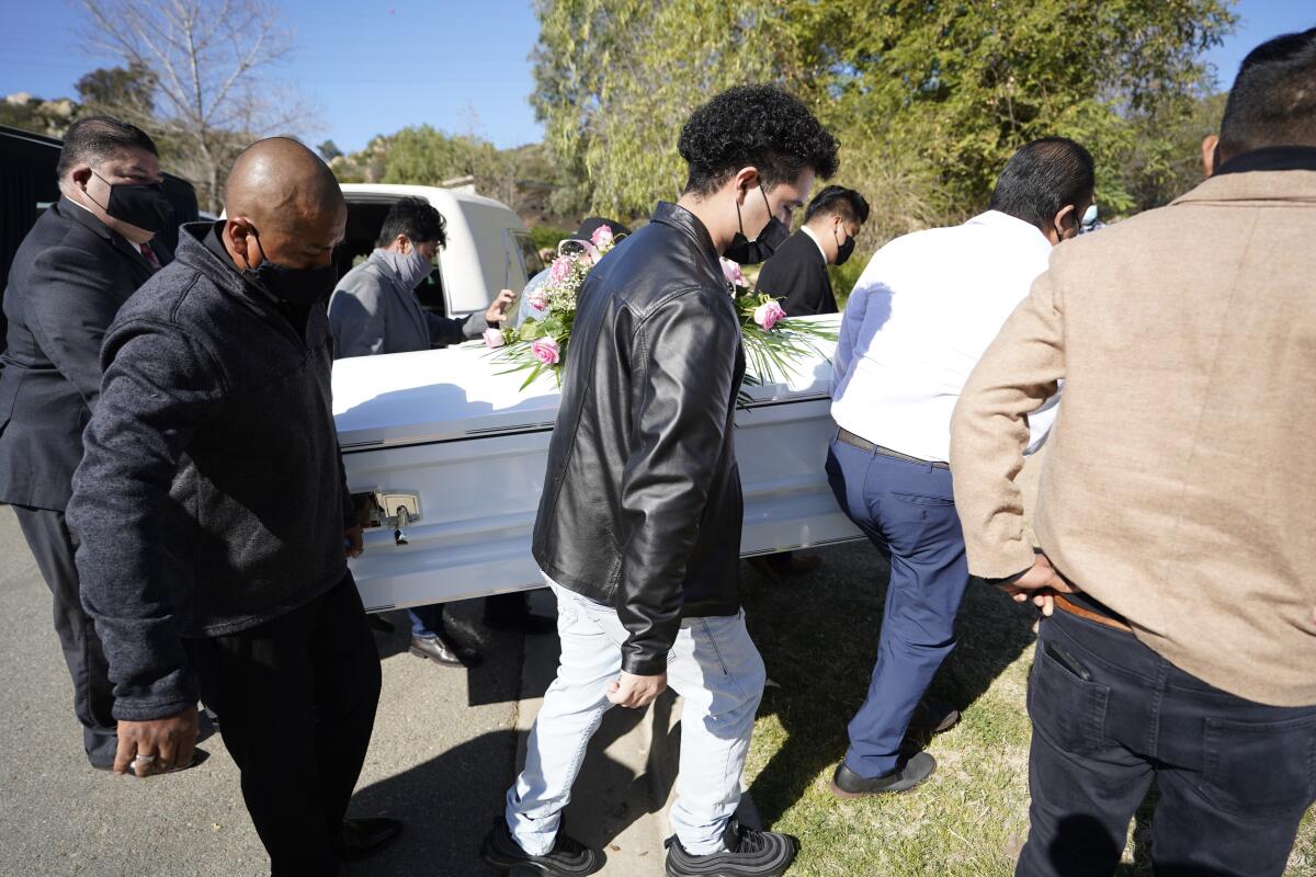 Pallbearers carry a white casket.