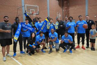 Members of the Bruin Fan Alliance pose on a basketball court.
