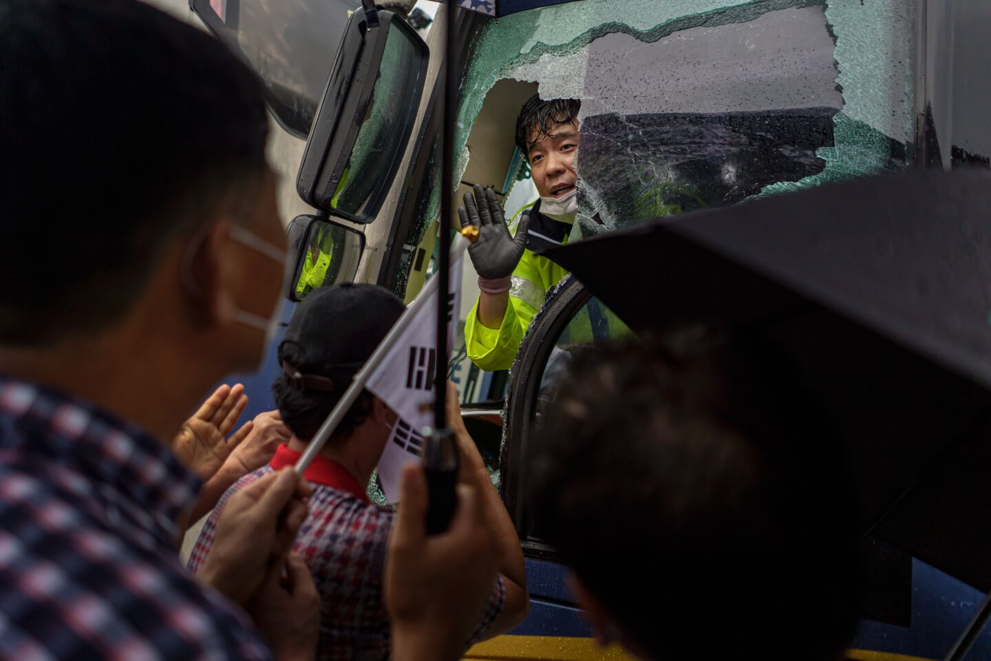 Protesters smash the window of a police bus.