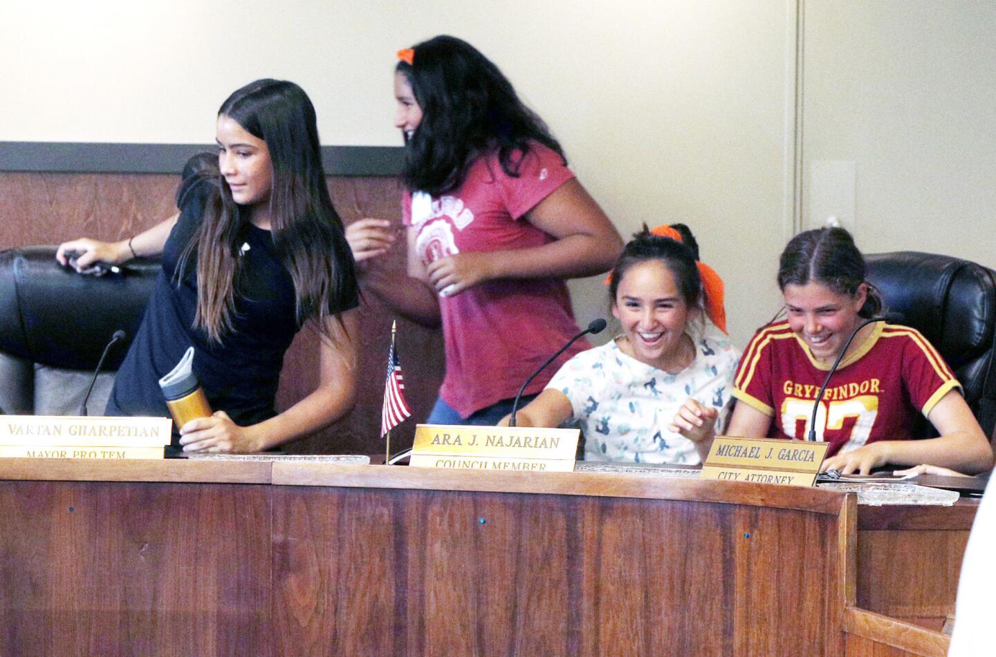 Young girls with Camp Rosie rush to fill the seats of the Glendale City Council during a tour of the Glendale City Hall in Glendale on Monday, July 9, 2018. Camp Rosie is a two-week summer day camp that provides 7th to 9th grade girls opportunities to learn trades and skills not often taught to young girls, as well as make connections with woman entrepreneurs and role models.