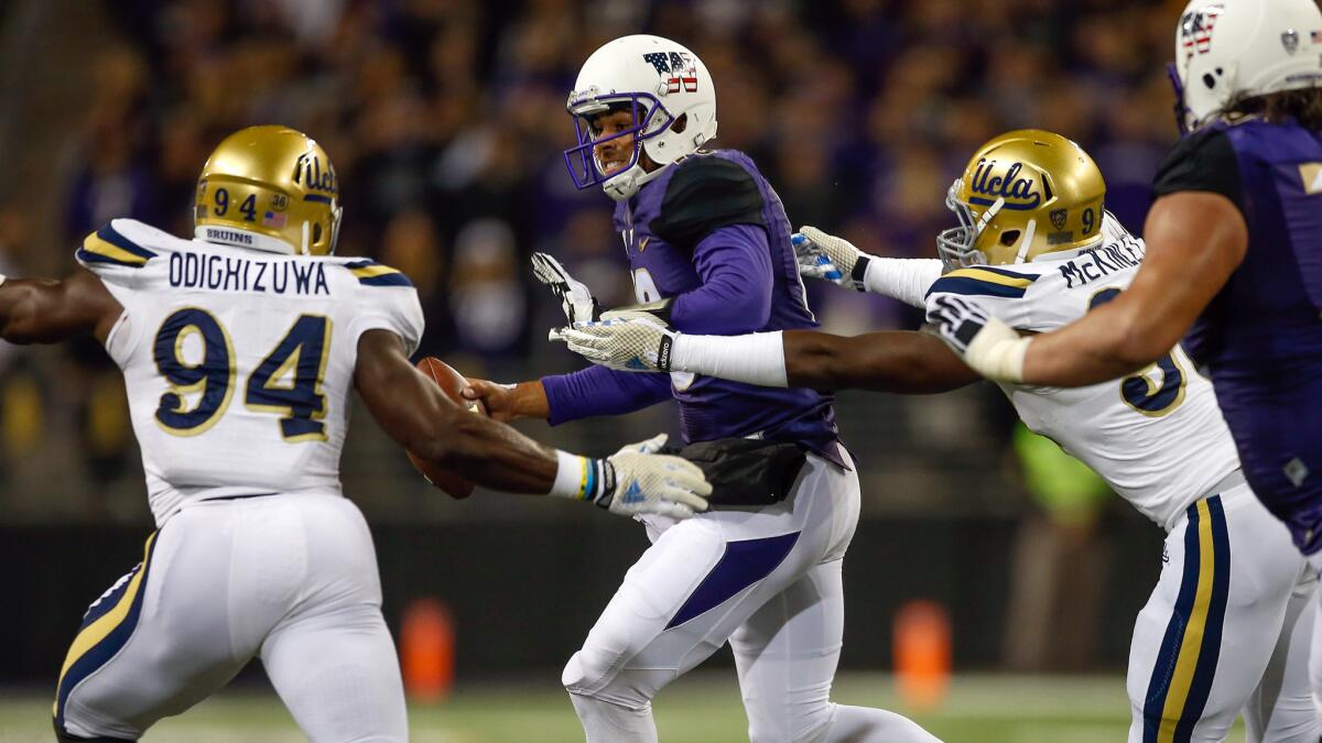 UCLA's Owamagbe Odighizuwa, left, and Takkarist McKinley, right, pressure Washington quarterback Cyler Miles during the Bruins' win Nov. 8.